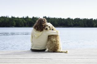 woman and long-haired dog sitting at the end of a dock