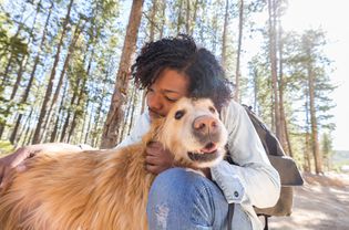 Man with old golden retriever outside.