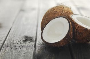 Two coconuts on wood surface, one cut in half