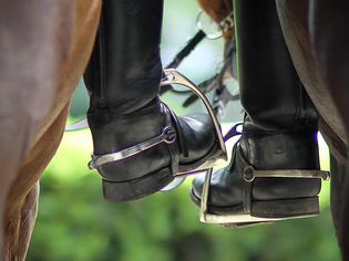 Closeup of horseback riders' boots in stirrups