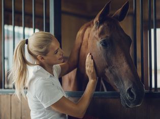 Woman with horse in stall.