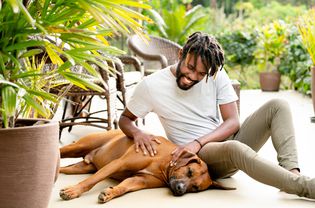 smiling man petting his dog in the backyard