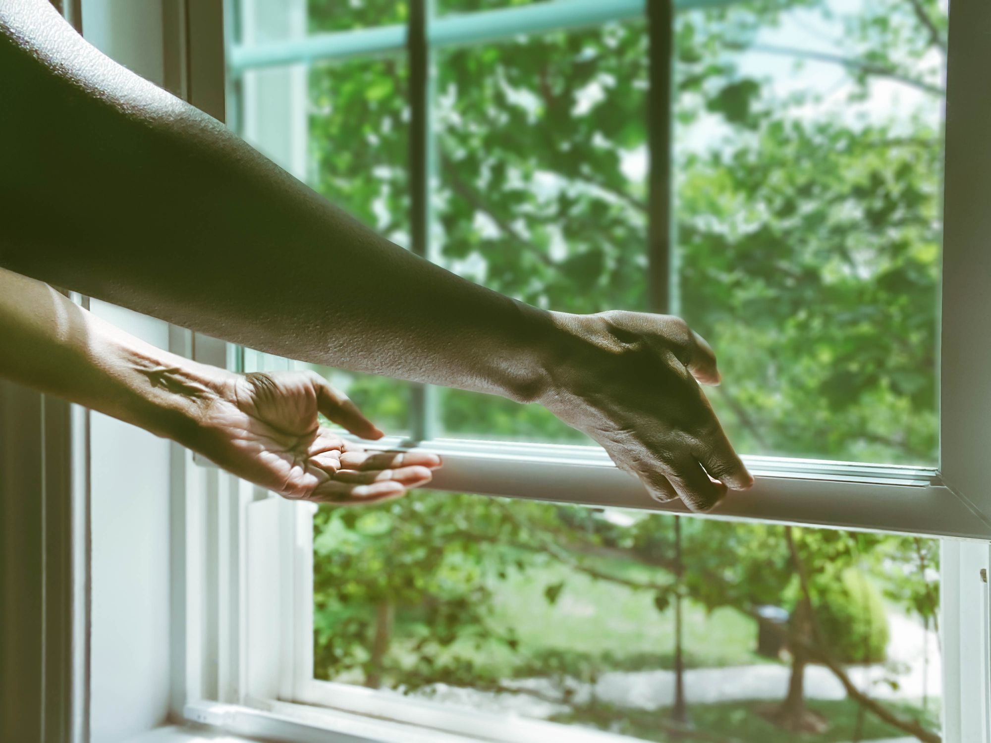 Woman's hands opening a window to the outside.