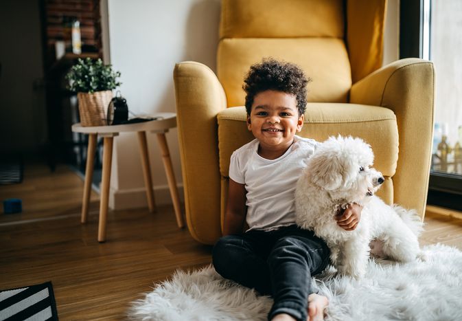 Child on floor with white dog.