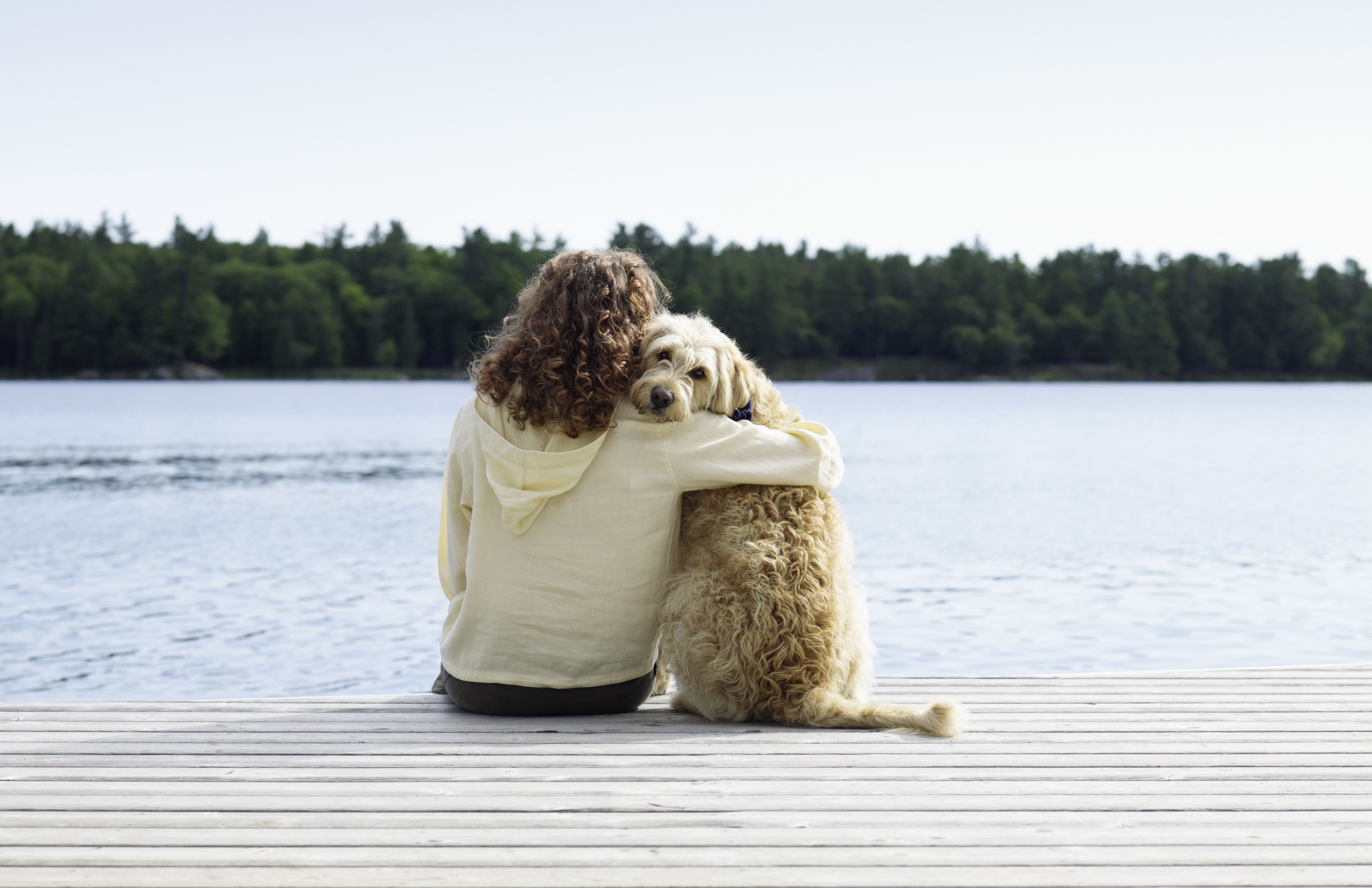 woman and long-haired dog sitting at the end of a dock